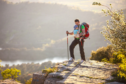Hiker with baby relaxing standing on cliff